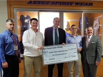 Staff and students hold up $1,000 donation from MA State Senator Jamie Eldridge to benefit our student scholarship fund!