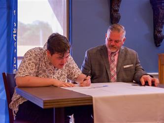 Superintendent-Director Ernest F. Houle with a student at a desk