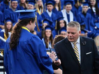 Superintendent-Director Ernest F. Houle giving a graduate their diploma 