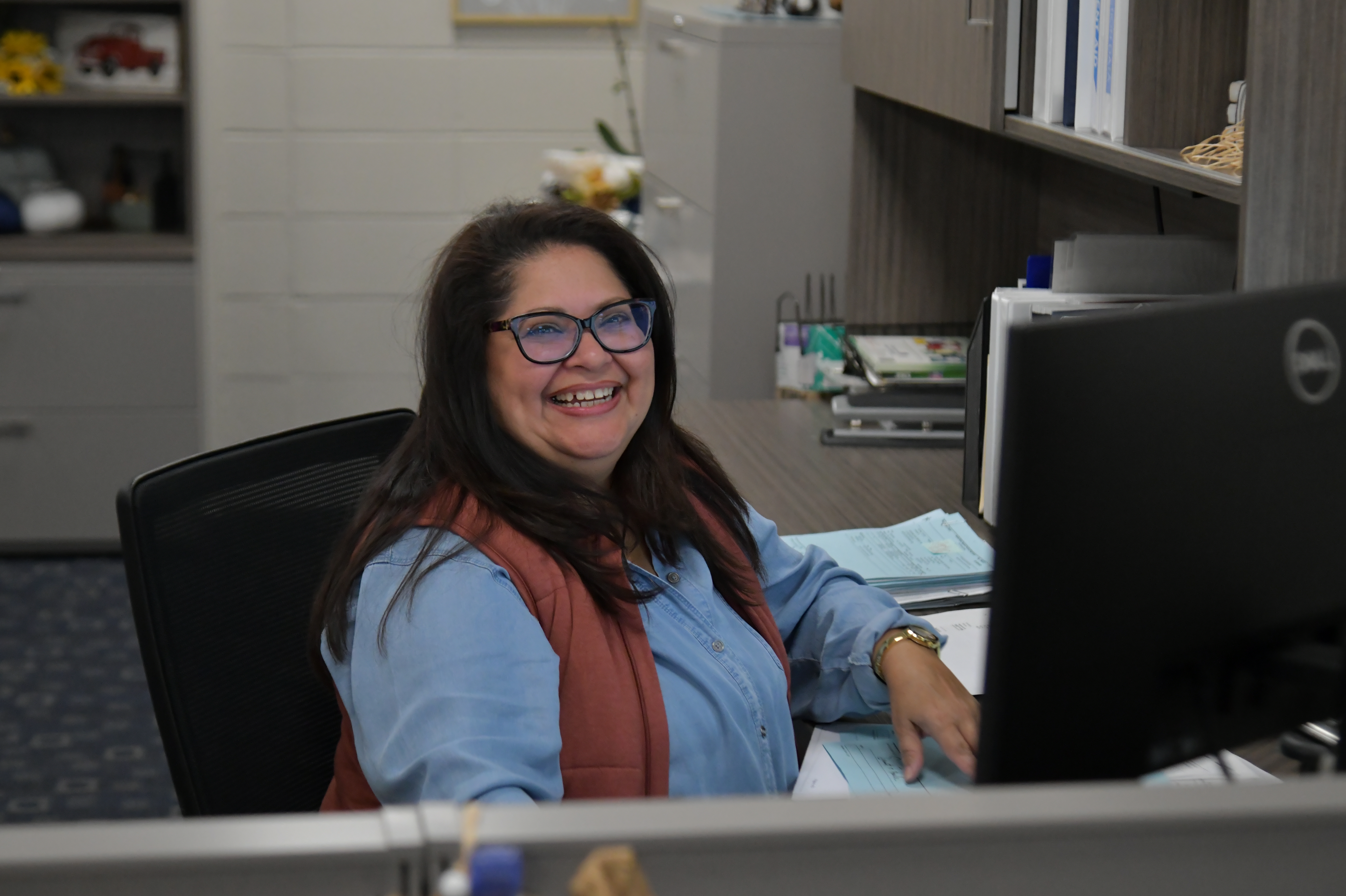 A person behind a desk reaching up to a hand with a check in it in an office setting