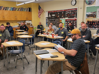 PAC members in desks of a classroom