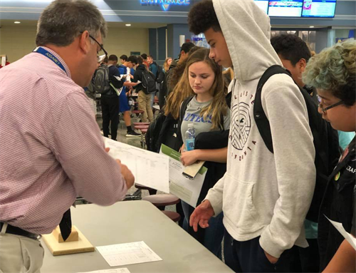 Students receiving schedules, with teachers helping them read the papers