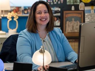 A smiling teacher at their desk