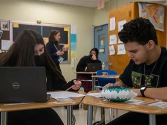 Students working together at desks side by side