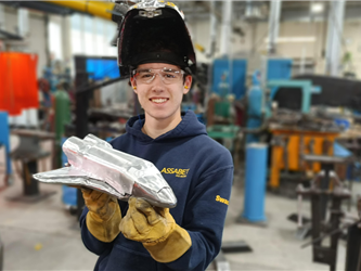A student holding up a spaceship they made out of metal