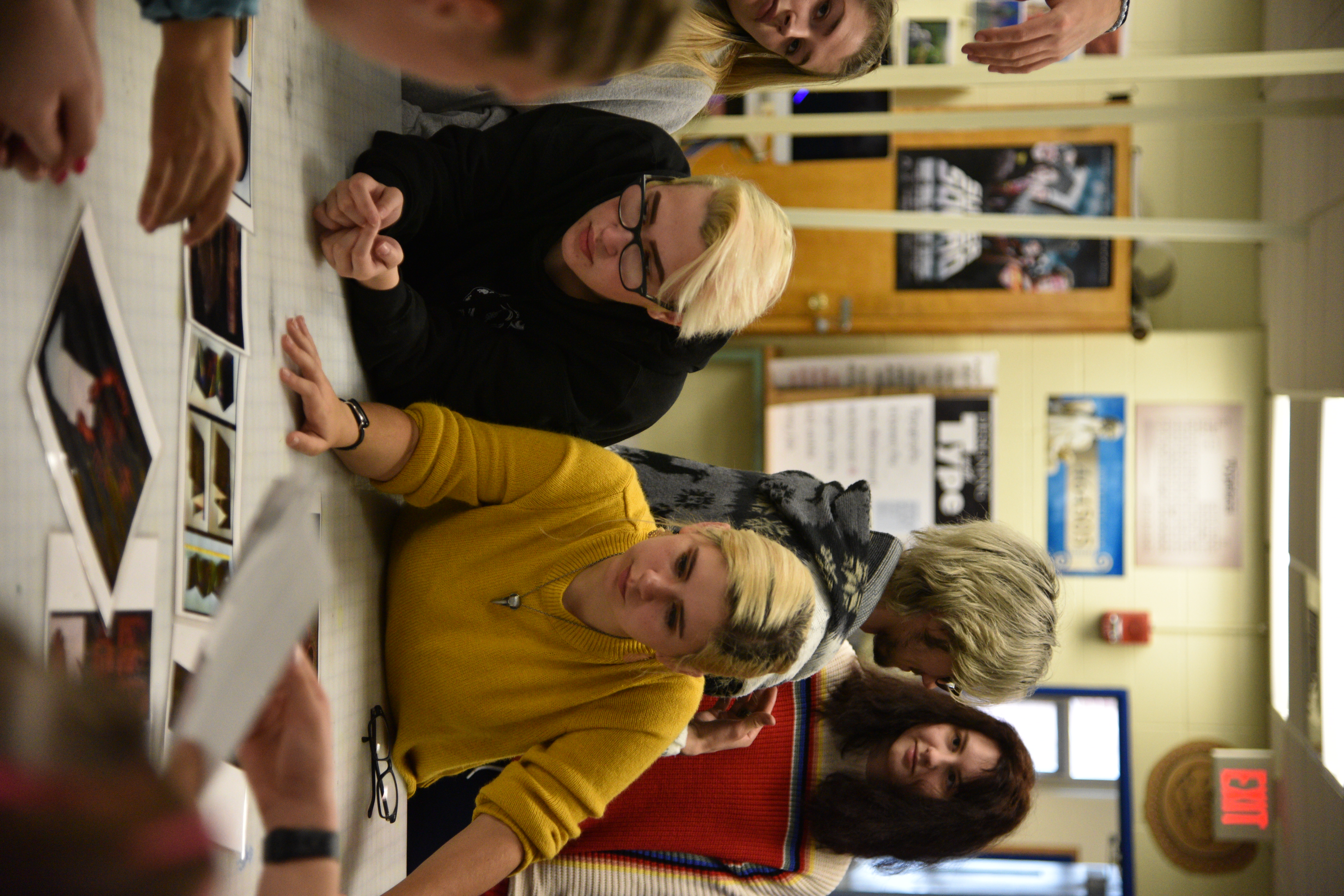 students looking over a table with pieces of a project laid out