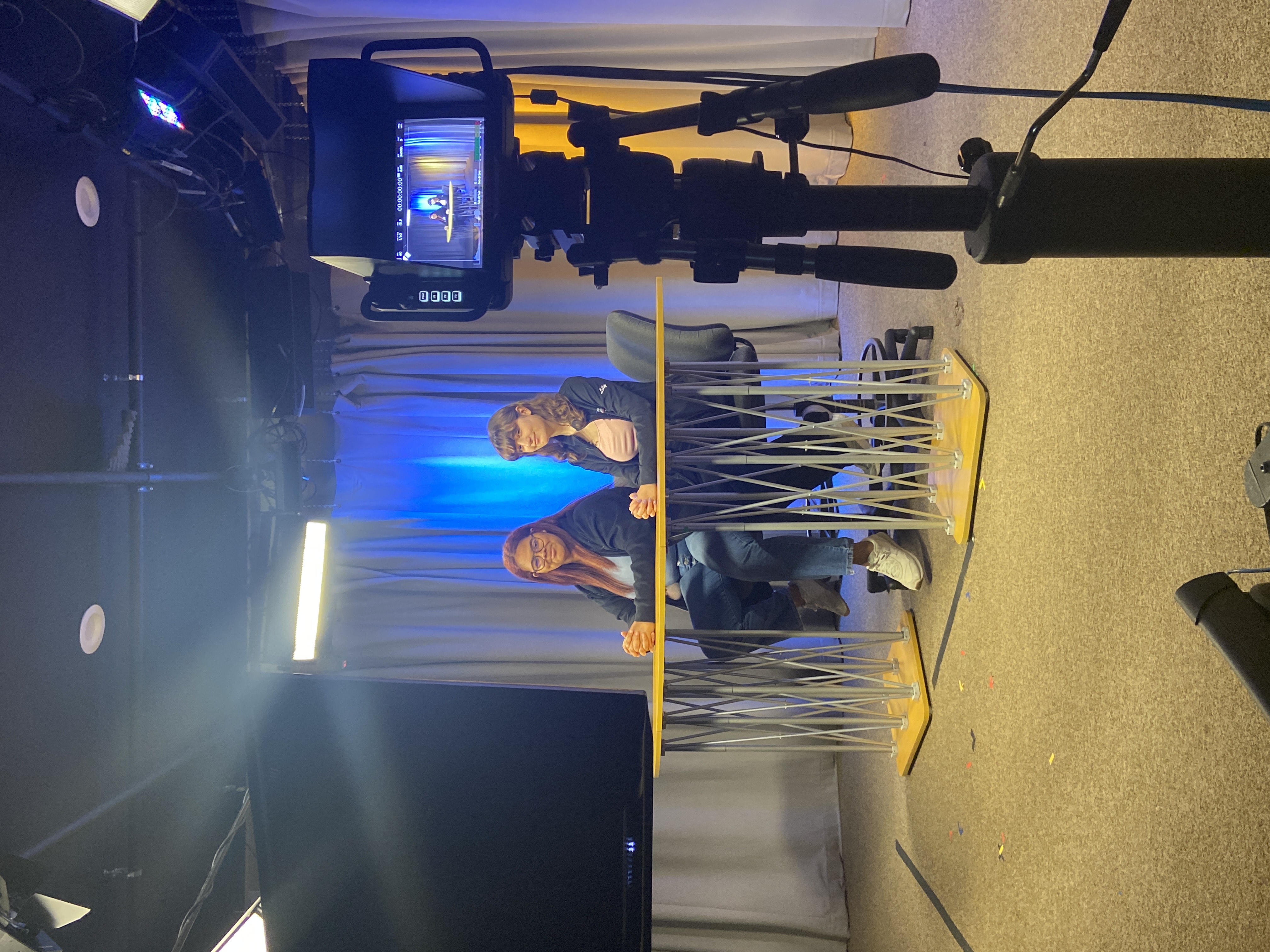 students at a desk on set in a TV production studio
